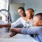 Children engaging in hand washing with their mother